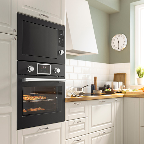 Cocina moderna con horno IKEA STENABY negro entre armarios blancos, eficiente y elegante.