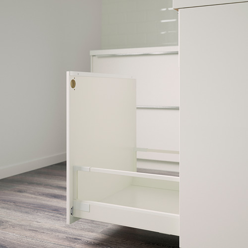 Accesorio de armario blanco, probablemente un conector de cajón, montado sobre un suelo de madera clara.