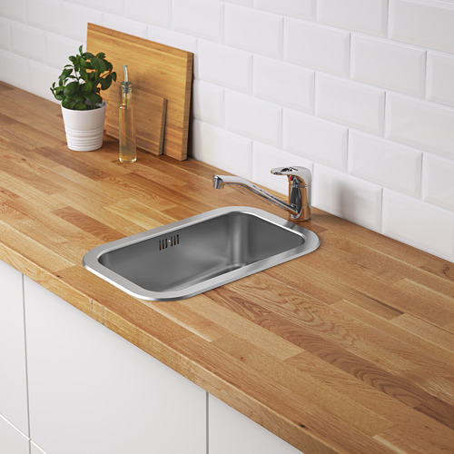 Pequeño fregadero de cocina de acero inoxidable incrustado en encimera de madera con grifo de plata.