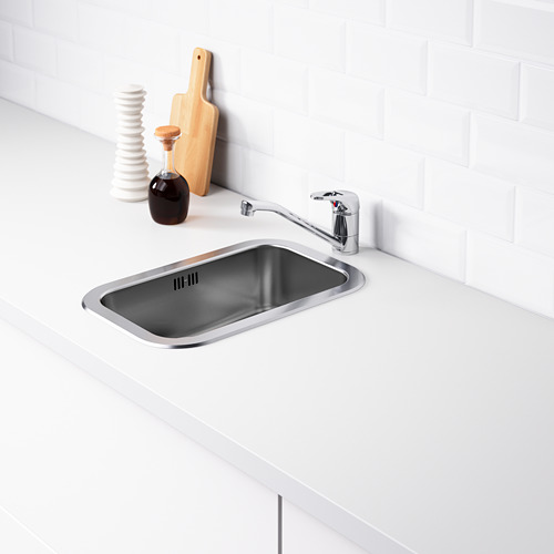 Fregadero de cocina de acero inoxidable con grifo y accesorios, contra pared de azulejos blancos.