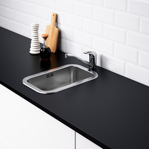 Fregadero de acero inoxidable con grifo, encimera negra, almohadilla de sonido, pared de azulejos blancos.