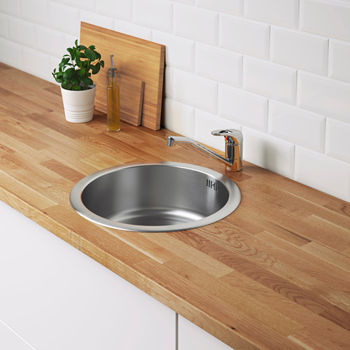 Fregadero de cocina de acero inoxidable en encimera de madera con grifería cromada.