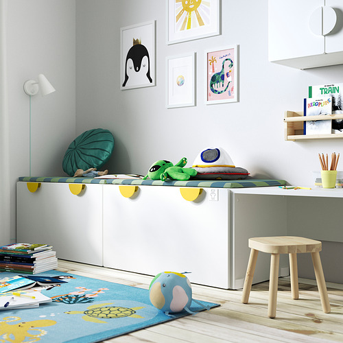 Zona de juegos para niños con banco SMÅSTAD blanco, juguetes de colores, alfombras, libros y arte mural.