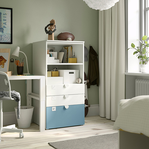 Habitación pequeña y acogedora con almacenamiento SMÅSTAD blanco, fútbol y arte. Paredes de color verde claro, escritorio, lámpara y ventana con cortinas transparentes.