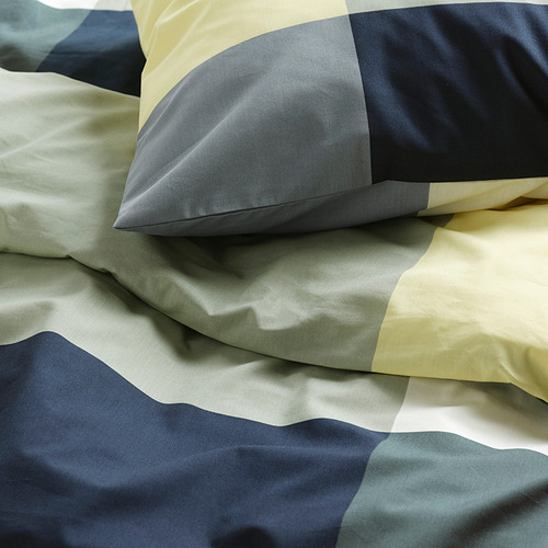 Primer plano de la ropa de cama cuidadosamente doblada con material suave y texturizado en colores apagados.