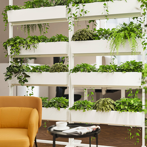 Pared de plantas modulares con plantas verdes, silla amarilla al lado.