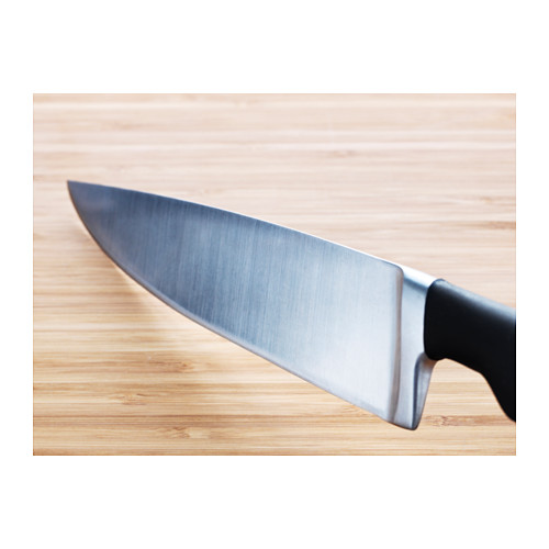 Cuchillo sobre tabla de madera, hoja afilada, mango negro.