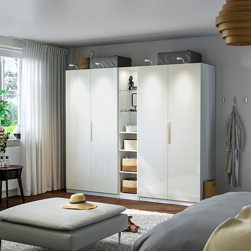 Dormitorio moderno con armario IKEA PAX , puertas de vidrio iluminadas, sofá gris, mesa de madera.