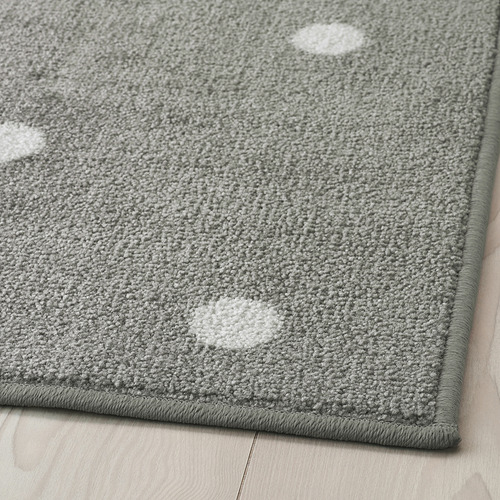 Alfombra rectangular gris con puntos blancos, colocada sobre un suelo de madera, con una superficie duradera y texturizada y un respaldo de goma seguro.