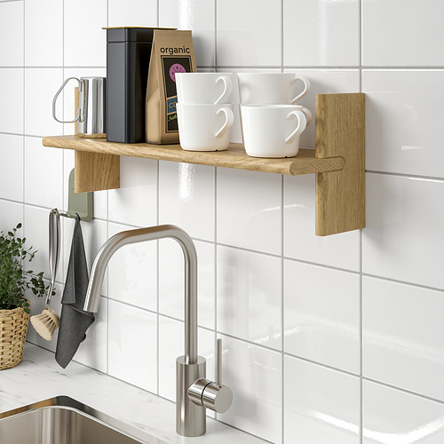 Una cocina moderna con un grifo de acero inoxidable, toallas colgantes, un estante de madera que sostiene tazas de café y accesorios contra una pared de azulejos.