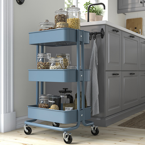 El carro rodante de tres niveles azul RÅSKOG, ideal para el almacenamiento en la cocina, cabe en espacios pequeños.