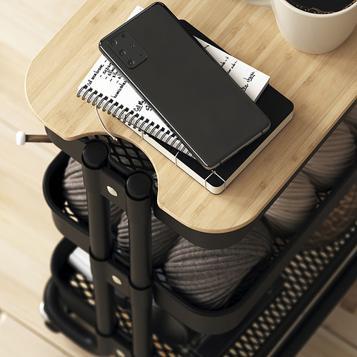 Pequeño carrito móvil negro con tapa de madera con capacidad para un teléfono inteligente, una computadora portátil y una taza, lo que brinda almacenamiento y espacio de trabajo versátiles.
