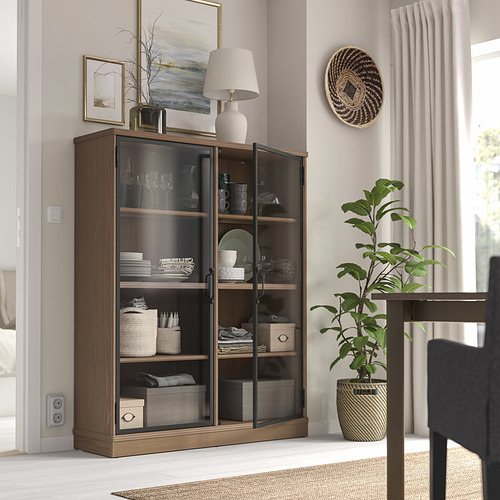 Gabinete LANESUND con puertas de vidrio, lámpara y decoración en una habitación espaciosa