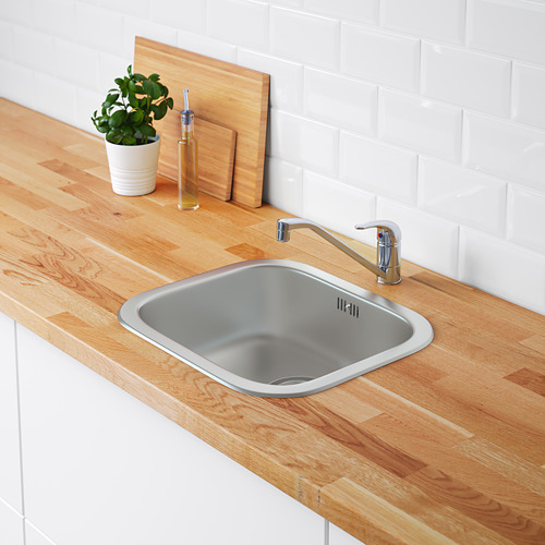 Encimera de madera con fregadero y grifo de acero inoxidable, pared de azulejos blancos.