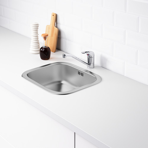 Fregadero de cocina de acero inoxidable con grifo sobre encimera blanca.