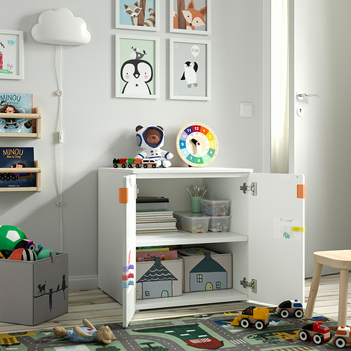 Habitación para niños con armario blanco para guardar juguetes y libros. Reloj, figura de oso y tren en la parte superior. Pies ajustables, bisagras de cierre suave.