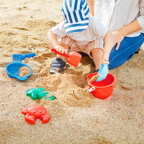 Niños jugando con juguetes de playa SANDIG: palas, cubos y moldes, potenciando la motricidad y la creatividad.