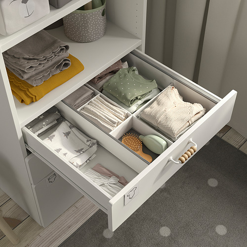 Organizador de cajones blanco abierto con ropa de bebé doblada y accesorios. Parte del sistema de almacenamiento SMÅSTAD para espacios pequeños.