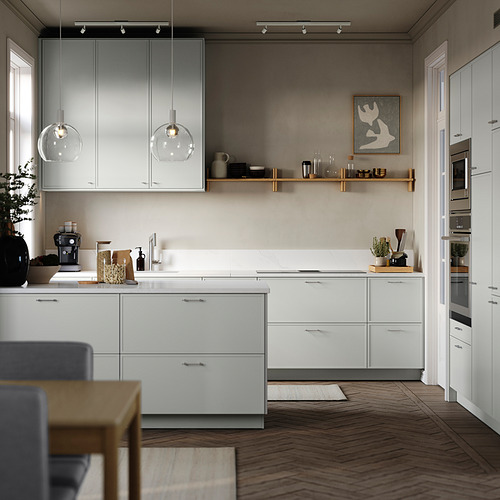 Cocina moderna con armarios blancos, electrodomésticos de acero inoxidable, luces colgantes, suelos de madera y objetos decorativos. Mesa de comedor centrada con sillas.
