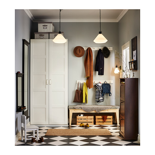 Un armario PAX blanco con múltiples compartimentos, complementado con baldosas a cuadros, un banco de madera y accesorios colgantes.