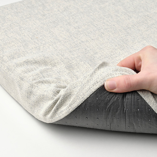 Persona sosteniendo cojín de tela gris doblado con textura.
