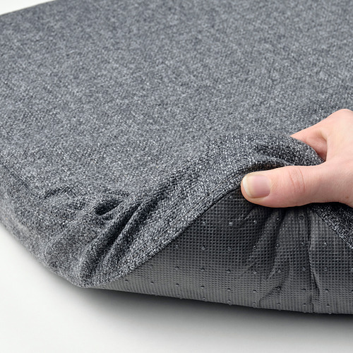 Una mano sostiene una almohadilla de silla gris de espuma viscoelástica con respaldo antideslizante, lo que garantiza estabilidad y comodidad.
