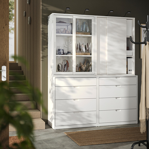 Mueble de almacenaje TONSTAD blanco con puertas y cajones de cristal, donde se exhiben elementos decorativos.