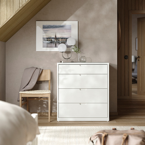 Dormitorio moderno con arcón blanco TONSTAD, banco de madera, lámpara y arte enmarcado.