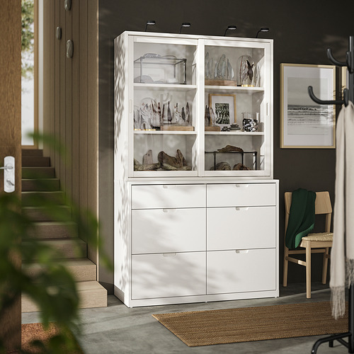 Moderno armario blanco roto con puertas y cajones de cristal que exhibe objetos de colección, con líneas limpias y cajones de cierre suave.