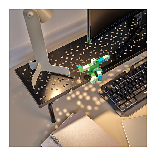 Configuración de escritorio de computadora con soporte para monitor, teclado y colorido juguete robot.