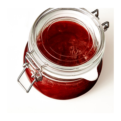 Un frasco de vidrio con un sello de cierre de metal, que contiene mermelada roja o conserva, que se utiliza para el almacenamiento de alimentos.