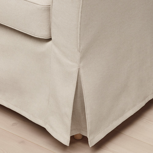 Falda de cama en tono neutro con estampado de espiga sobre suelo de madera.