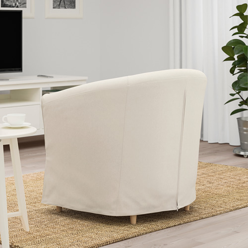 Un sillón TULLSTA de color crema con cojín, perfecto para espacios reducidos, colocado sobre una alfombra de yute.