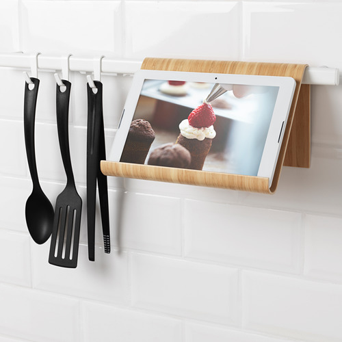 Soporte para tabletas y utensilios de cocina en la pared, que muestra la receta del postre y cuelga espátula, cucharón y pinza.