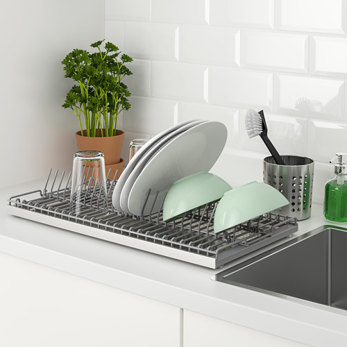 Escurridor de platos de cocina en el mostrador para almacenar los artículos lavados. Contiene platos, tazas y cubiertos, con una bandeja extraíble para recoger agua.