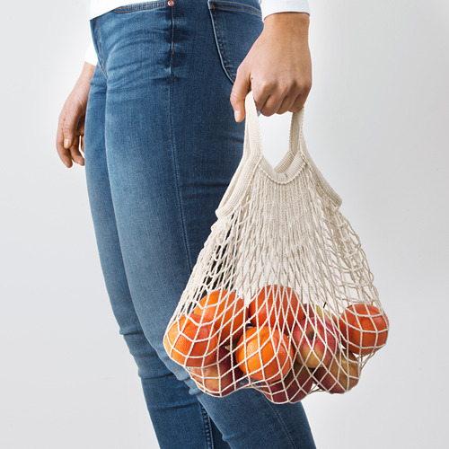 Persona sosteniendo una bolsa de red reutilizable llena de naranjas, promoviendo las compras ecológicas.