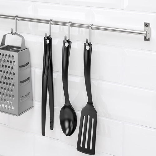Los utensilios de cocina cuelgan de un riel de acero inoxidable: rallador, pinzas, cuchara, espátula. Ahorro de espacio.