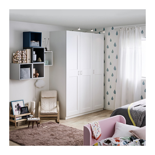 Guardería moderna con armario GRIMO blanco, estanterías, silla rosa, cortinas con estampados de gotas de lluvia, alfombra acogedora y cama acolchada.