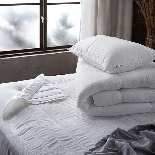 Dos almohadas blancas apiladas sobre una cama sin hacer, una más grande que la otra.