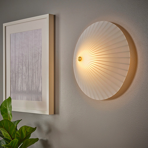 Una moderna lámpara de pared redonda con pantalla de cristal opal, montada sobre una pared gris a la derecha de una foto enmarcada, que proyecta una luz suave.