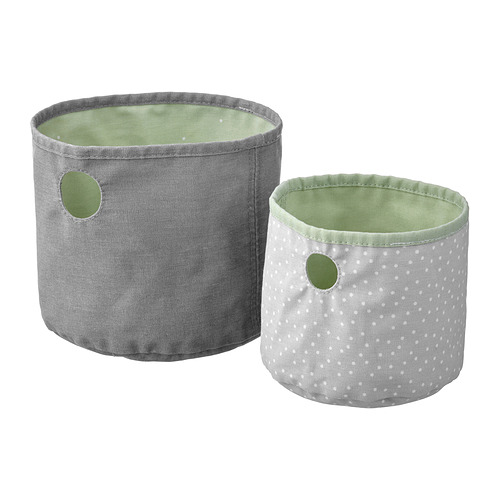 Dos cestas de almacenamiento redondas y reversibles, una gris y otra blanca con lunares, fabricadas en poliéster reciclado en colores pastel.