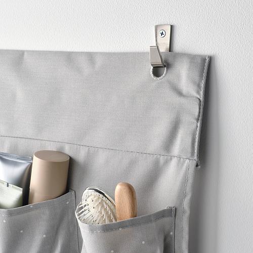 Organizador colgante gris con bolsillos para guardar objetos, unido a un gancho de pared. Ideal para guardar artículos esenciales del baño o artículos para bebés.