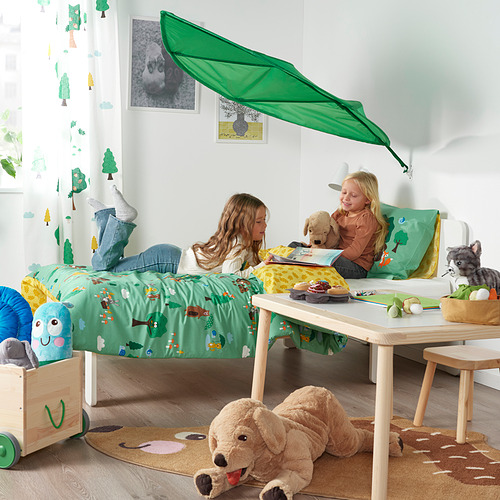 Habitación para niños con cama con dosel verde, dos niñas jugando, animales de peluche y juguetes.