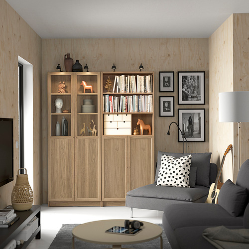 Sala de estar con estanterías Billy, sofá gris y mesa de centro redonda.