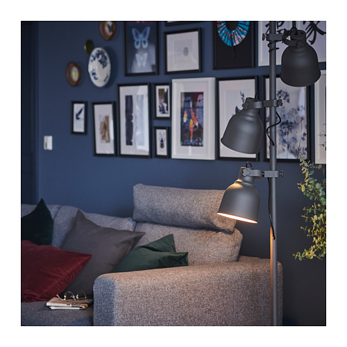 Acogedora sala de estar con sofá VIMLE en gris, almohadas de colores, lámpara de pie moderna y pared azul con marcos de fotos.