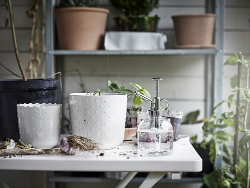 Macetas de cerámica blanca, puntos texturizados, en estantería blanca con plantas.