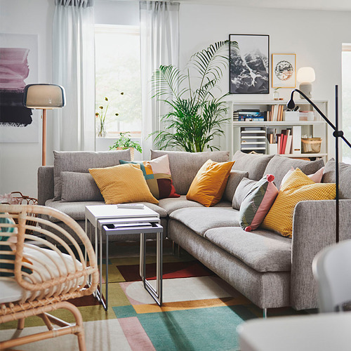 Sala de estar moderna con sofá SÖDERHAMN gris, cojines de colores, silla de mimbre y plantas.