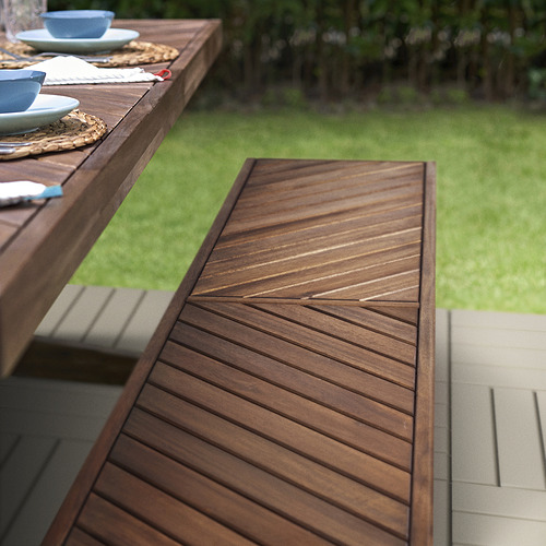 Banco de exterior de madera con motivo de espiga de NORRMANSÖ. Color marrón oscuro, banco amplio con mesa de comedor.