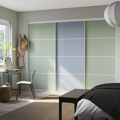 Dormitorio moderno con puertas corredizas de color verde claro, una silla blanca y un piso de madera.