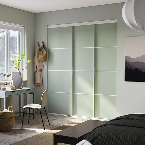 Dormitorio moderno con puertas de armario de vidrio esmerilado verde claro, piso de madera y decoración minimalista.